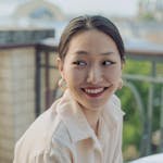 Cheerful woman smiling while dining outdoors, exuding happiness and warmth.