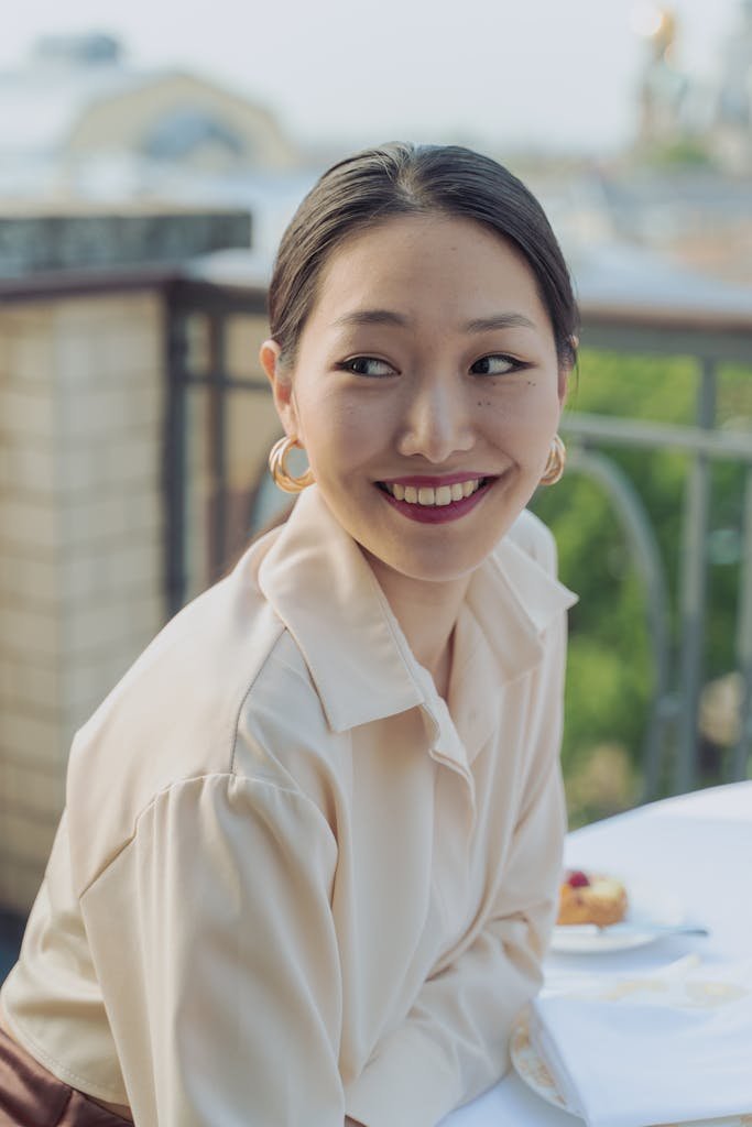 Cheerful woman smiling while dining outdoors, exuding happiness and warmth.
